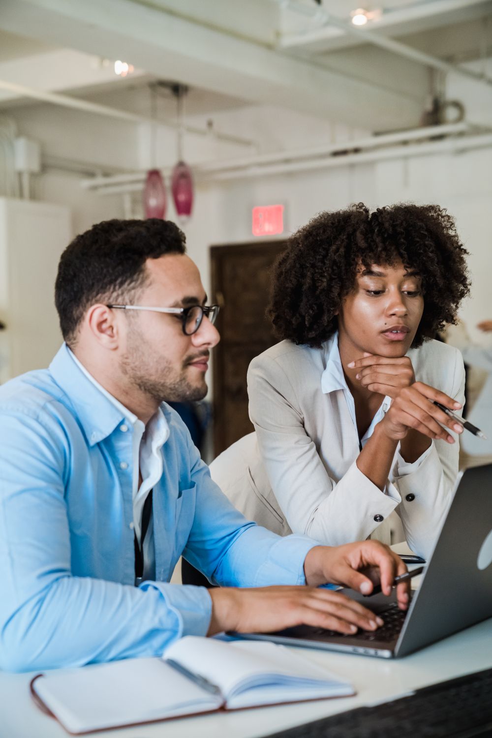 Two business professionals collaborating at a laptop in a modern office.